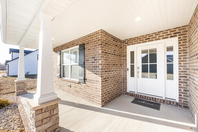 doorway to property featuring brick siding and a porch