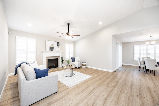 living room with lofted ceiling, light wood-style floors, a healthy amount of sunlight, and a fireplace with raised hearth