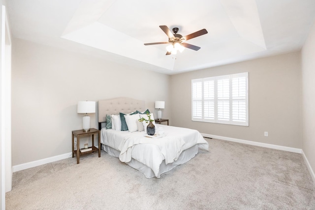 bedroom with ceiling fan, a raised ceiling, baseboards, and carpet floors