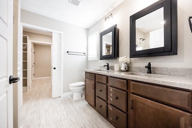 bathroom featuring double vanity, toilet, visible vents, and a sink