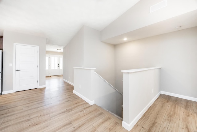 hallway featuring visible vents, an upstairs landing, lofted ceiling, and wood finished floors