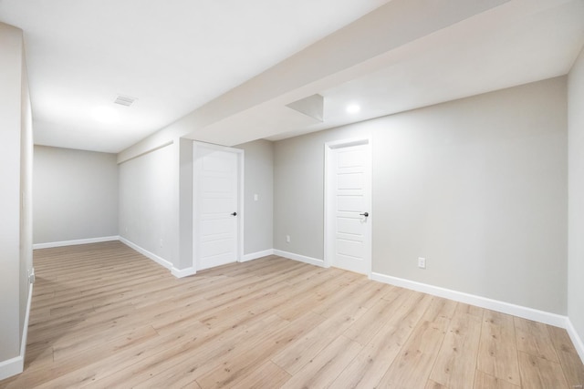 finished basement with visible vents, baseboards, and light wood-style floors