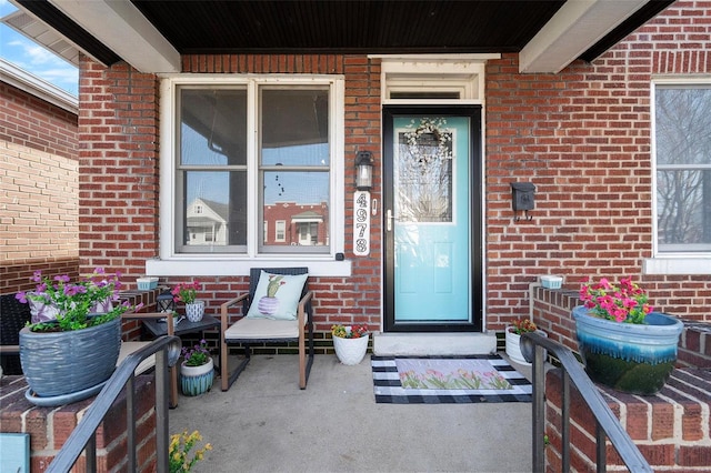 doorway to property with brick siding and a porch