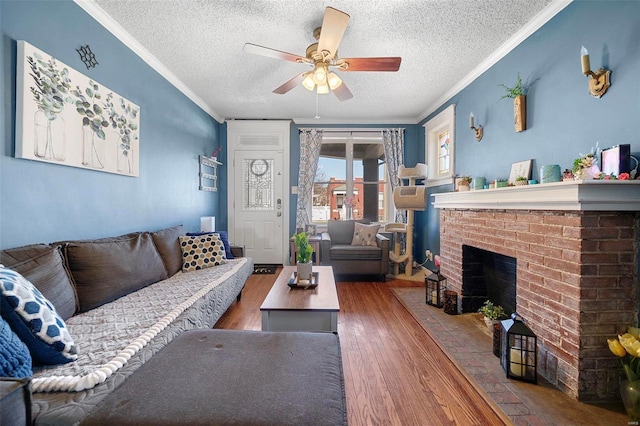 living area featuring a textured ceiling, a fireplace, wood finished floors, a ceiling fan, and ornamental molding