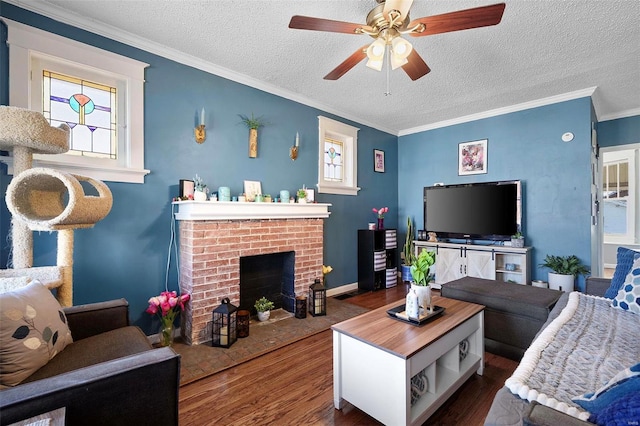 living room with a textured ceiling, a fireplace, wood finished floors, a ceiling fan, and ornamental molding