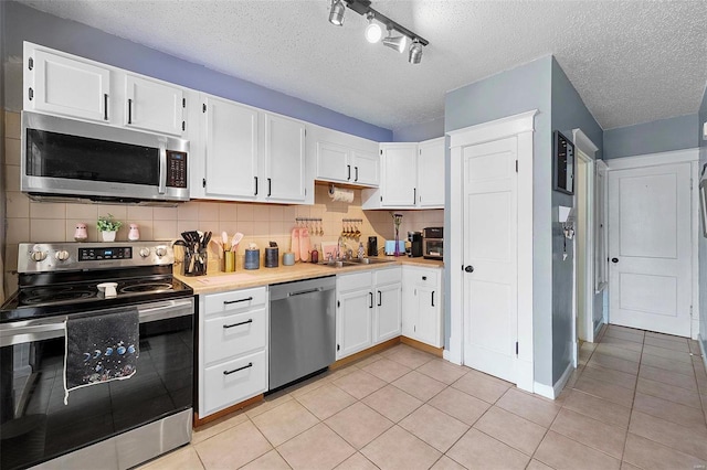 kitchen with light tile patterned floors, tasteful backsplash, light countertops, appliances with stainless steel finishes, and a sink