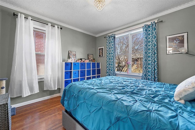 bedroom with baseboards, a textured ceiling, ornamental molding, and wood finished floors