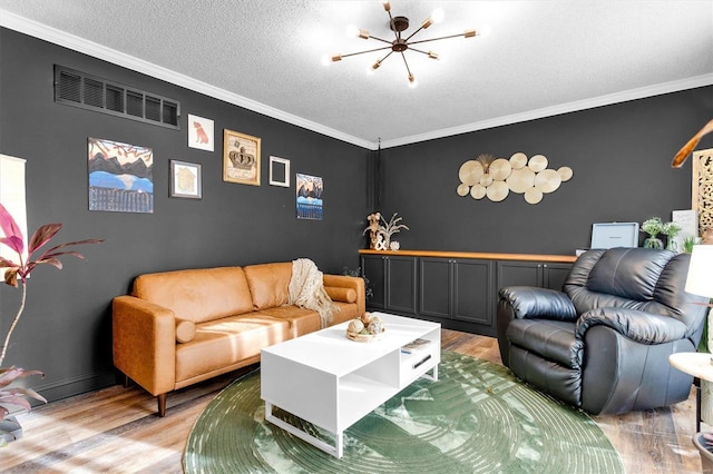 living room with visible vents, light wood-style floors, a textured ceiling, crown molding, and a chandelier