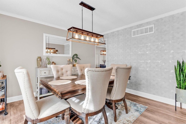 dining area featuring visible vents, baseboards, wood finished floors, and crown molding