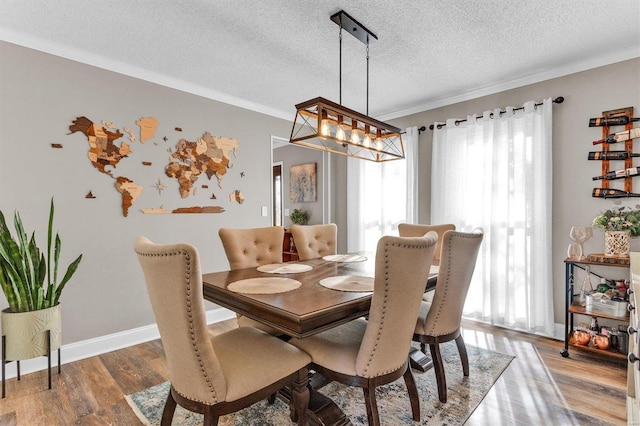 dining area with crown molding, wood finished floors, baseboards, and a textured ceiling