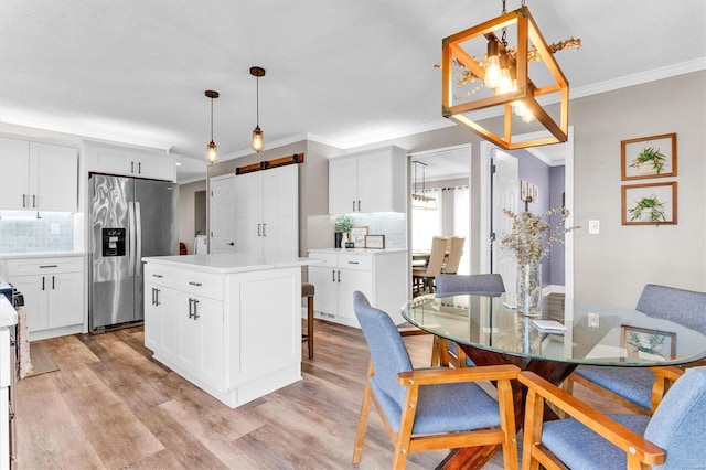 kitchen featuring a barn door, light wood-style flooring, crown molding, and stainless steel refrigerator with ice dispenser