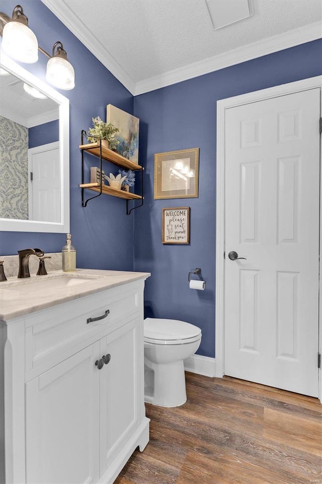 bathroom featuring crown molding, baseboards, toilet, wood finished floors, and vanity