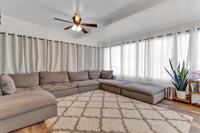 living area featuring beamed ceiling, a ceiling fan, and wood finished floors