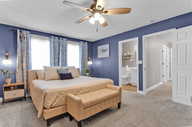 carpeted bedroom featuring connected bathroom, baseboards, a textured ceiling, and a ceiling fan