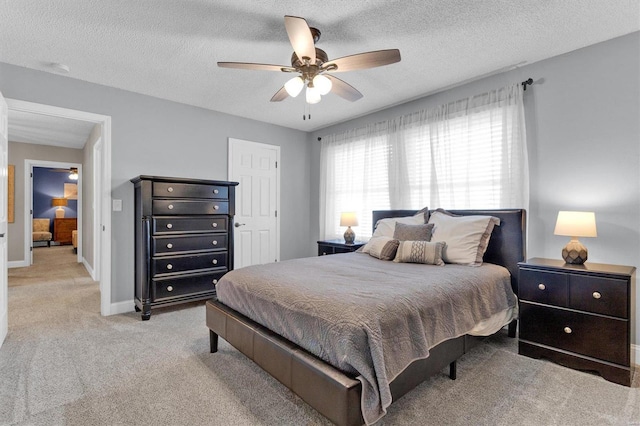 carpeted bedroom with ceiling fan, a textured ceiling, and baseboards