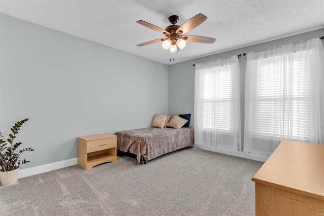 bedroom featuring light colored carpet, a textured ceiling, baseboards, and a ceiling fan