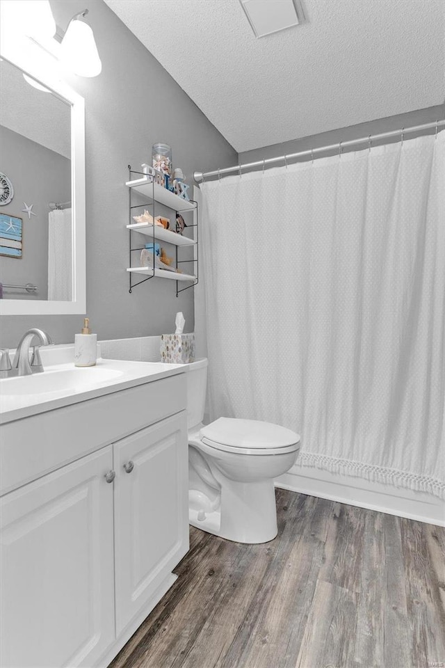 full bath featuring vanity, wood finished floors, a textured ceiling, curtained shower, and toilet