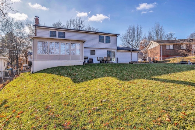 rear view of property with a yard, fence, a sunroom, and a chimney