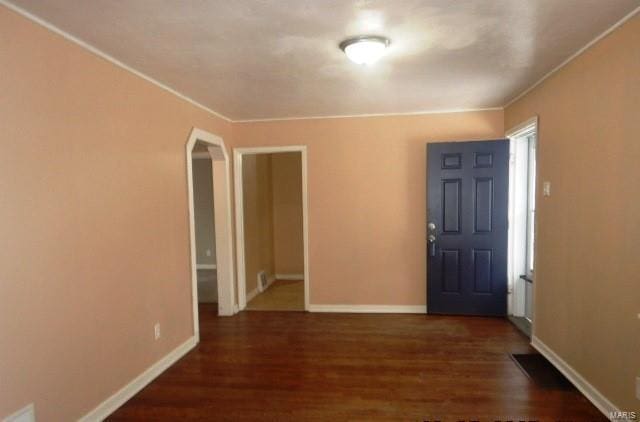 foyer entrance with baseboards, arched walkways, and wood finished floors