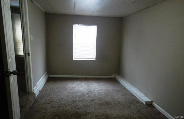 carpeted empty room with a paneled ceiling and baseboards