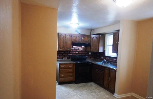 kitchen featuring tasteful backsplash, dark countertops, a sink, under cabinet range hood, and black / electric stove