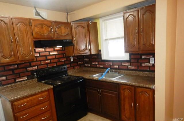 kitchen with brown cabinetry, black electric range oven, a sink, and under cabinet range hood