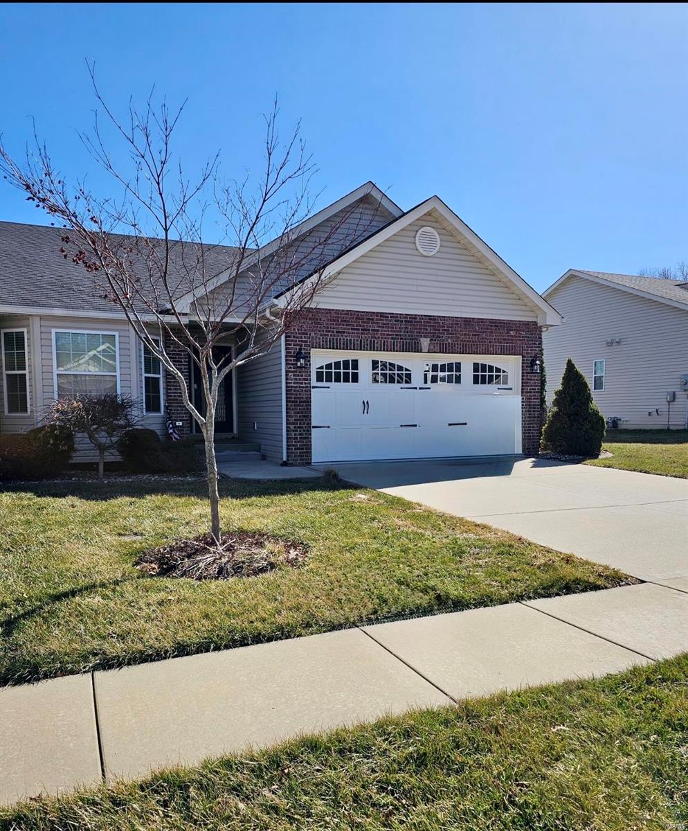 ranch-style house featuring a garage, concrete driveway, brick siding, and a front yard