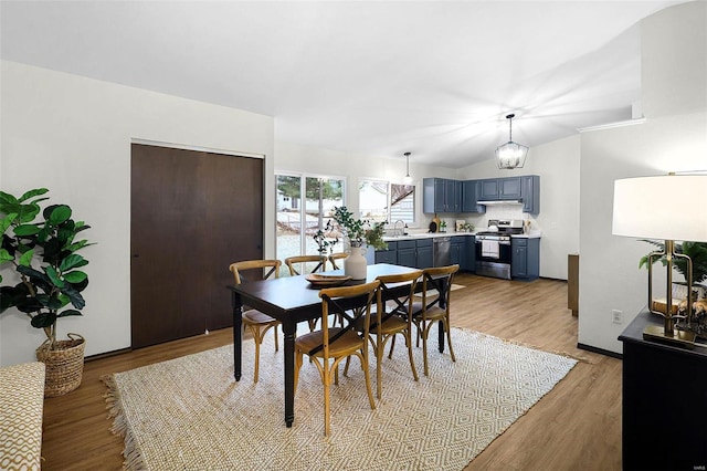 dining room featuring vaulted ceiling, light wood finished floors, baseboards, and a notable chandelier