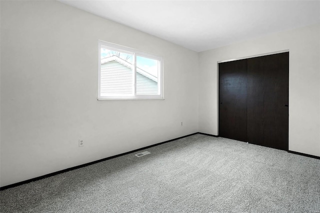 unfurnished bedroom featuring carpet, a closet, visible vents, and baseboards