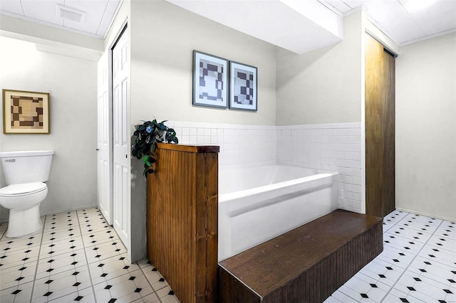 full bath featuring tile patterned floors, toilet, and a bath