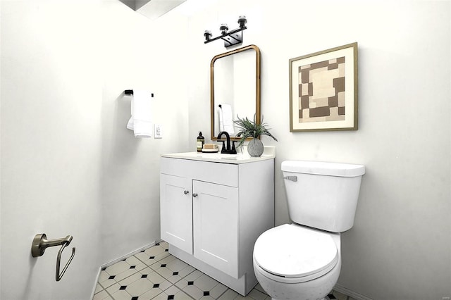 half bathroom with toilet, tile patterned floors, and vanity