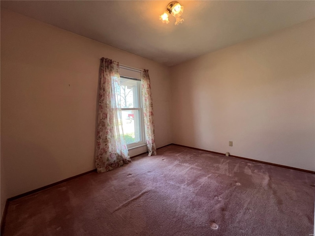 carpeted empty room featuring baseboards