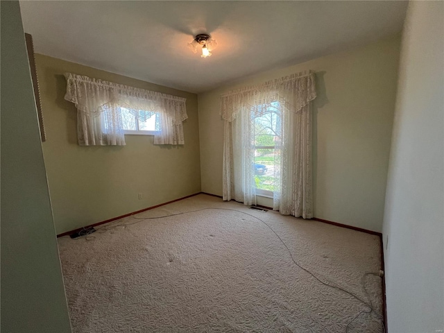 spare room featuring carpet floors and baseboards