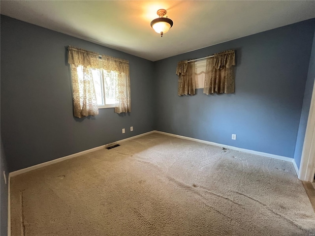 unfurnished room with baseboards, visible vents, and carpet