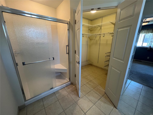 full bath with a spacious closet, tile patterned flooring, and a stall shower