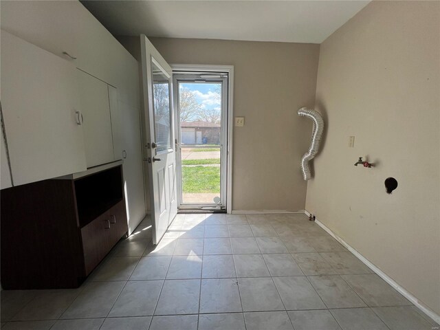 doorway featuring baseboards and light tile patterned floors