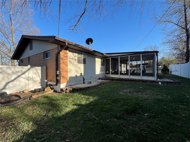 back of house featuring a sunroom, a fenced backyard, and a lawn