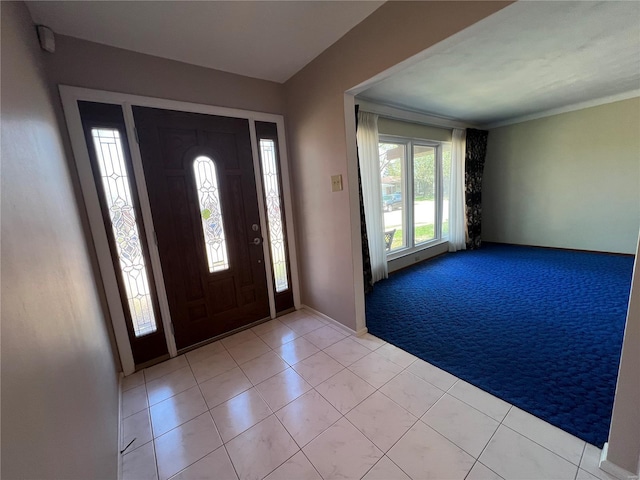 foyer with light carpet, baseboards, and light tile patterned floors