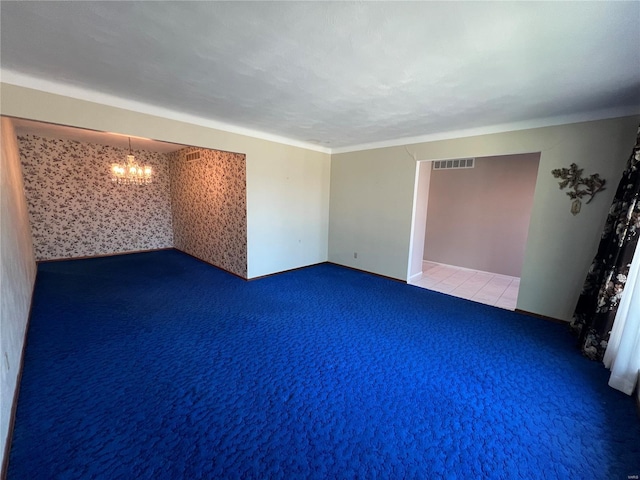 carpeted spare room with baseboards, visible vents, and a chandelier
