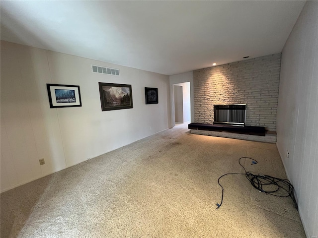 unfurnished living room with a brick fireplace, visible vents, and carpet