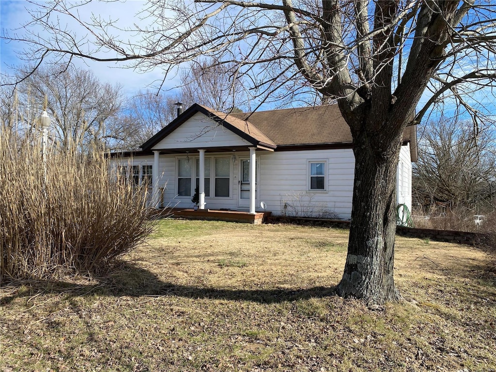 view of front of home featuring a porch, a front yard, and a shingled roof