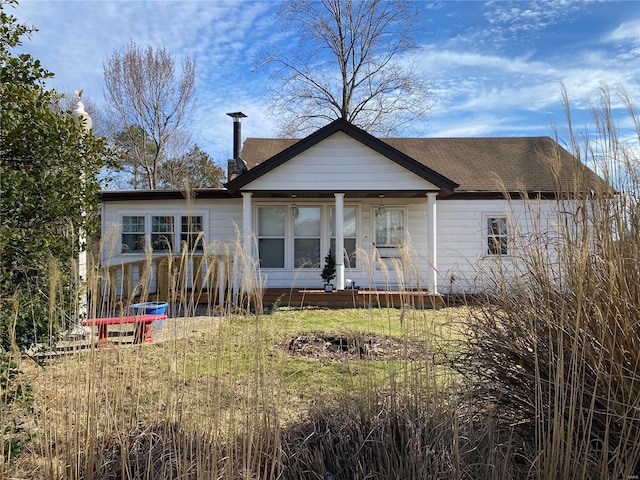 rear view of property with a shingled roof and a chimney