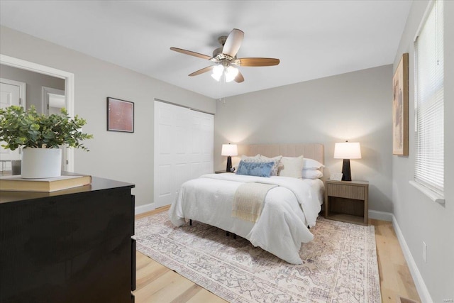 bedroom featuring light wood-style floors, baseboards, a closet, and ceiling fan