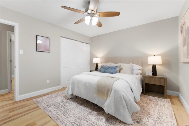 bedroom featuring light wood-type flooring, baseboards, a closet, and a ceiling fan