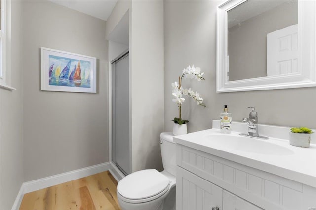 bathroom featuring baseboards, toilet, wood finished floors, and a shower stall