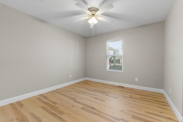 spare room with baseboards, light wood-style floors, and a ceiling fan