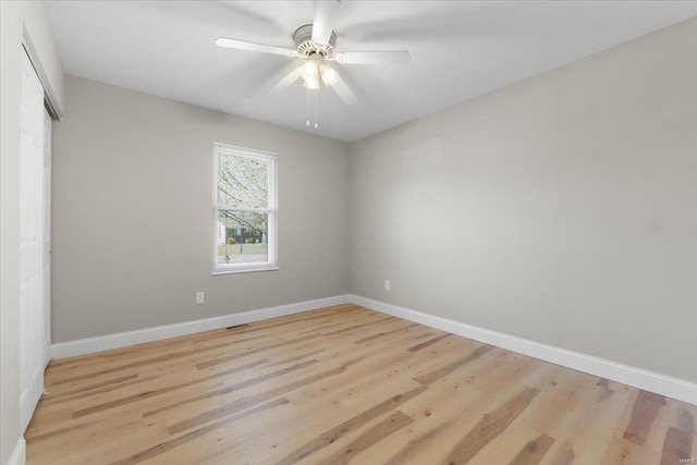 empty room featuring light wood finished floors, a ceiling fan, and baseboards