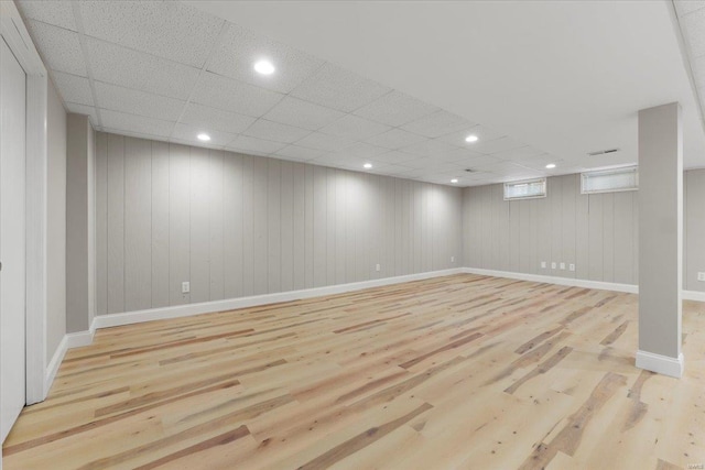 basement featuring recessed lighting, wood finished floors, baseboards, and a paneled ceiling