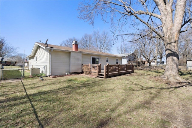 rear view of property featuring fence, a lawn, a chimney, a deck, and a gate