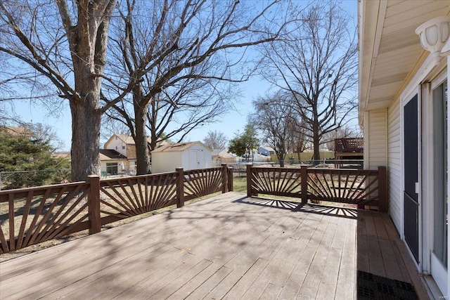 wooden deck featuring an outdoor structure, fence, and a shed